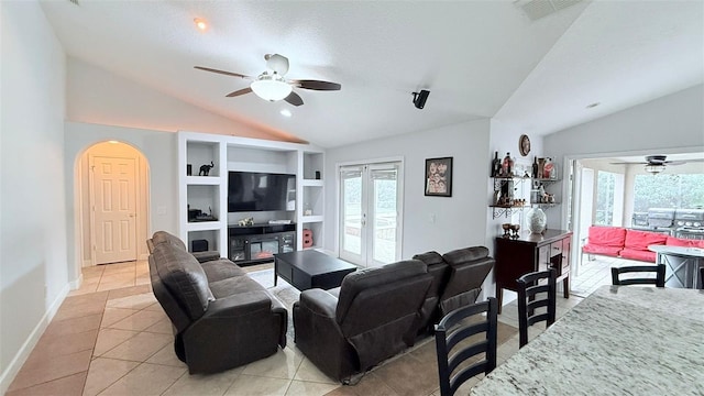 tiled living room featuring ceiling fan, a textured ceiling, built in shelves, french doors, and vaulted ceiling