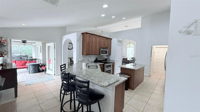 kitchen featuring light tile patterned floors, vaulted ceiling, kitchen peninsula, and appliances with stainless steel finishes