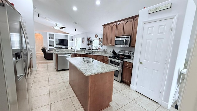 kitchen with light stone countertops, appliances with stainless steel finishes, a center island, kitchen peninsula, and vaulted ceiling