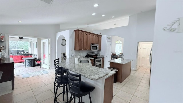 kitchen featuring light tile patterned flooring, kitchen peninsula, stainless steel appliances, and vaulted ceiling