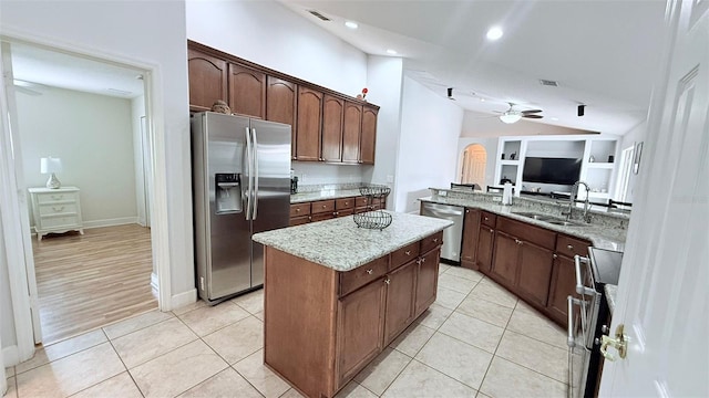 kitchen with a center island, sink, built in features, stainless steel appliances, and light tile patterned flooring