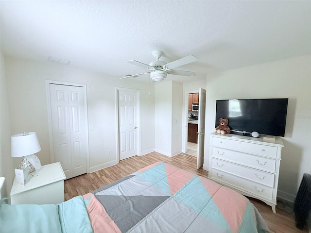 bedroom with a textured ceiling, light hardwood / wood-style flooring, and ceiling fan