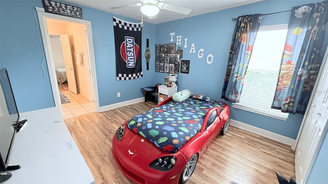 bedroom with ceiling fan, connected bathroom, multiple windows, and hardwood / wood-style flooring