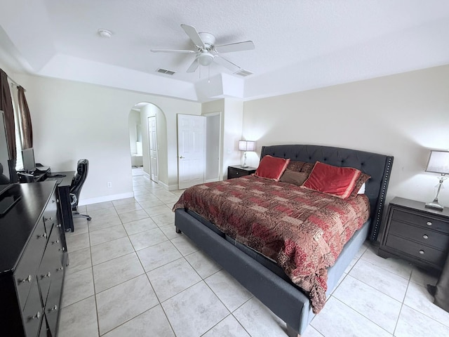 bedroom with ceiling fan, a textured ceiling, a raised ceiling, and light tile patterned flooring