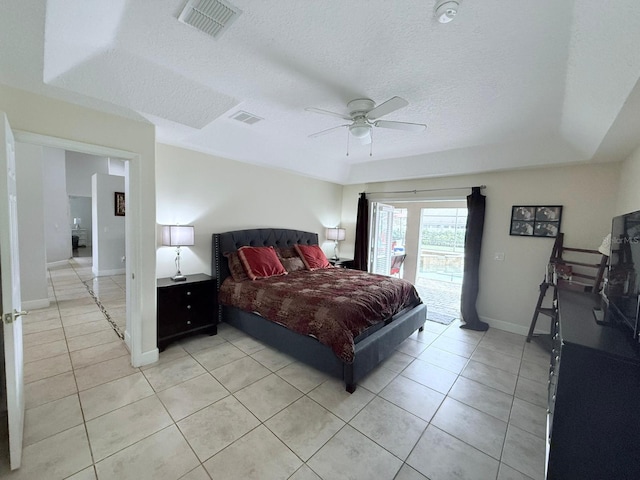 tiled bedroom featuring ceiling fan, access to exterior, a textured ceiling, and a tray ceiling