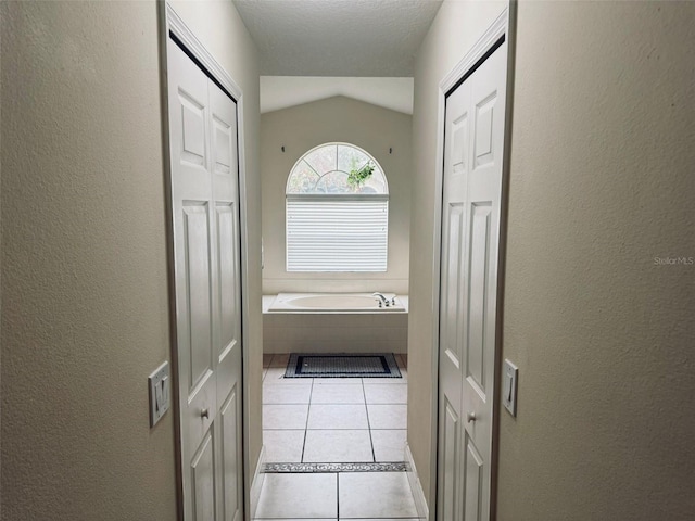 corridor featuring light tile patterned floors and vaulted ceiling