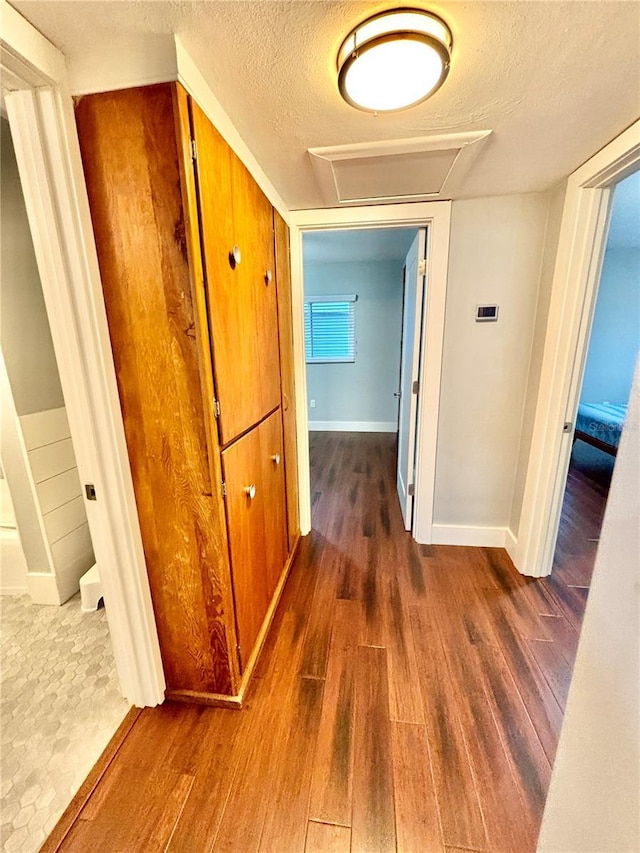 hallway featuring dark wood-type flooring and a textured ceiling