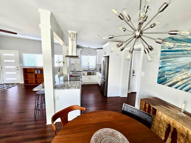 dining area with an inviting chandelier, dark hardwood / wood-style floors, sink, and ornate columns