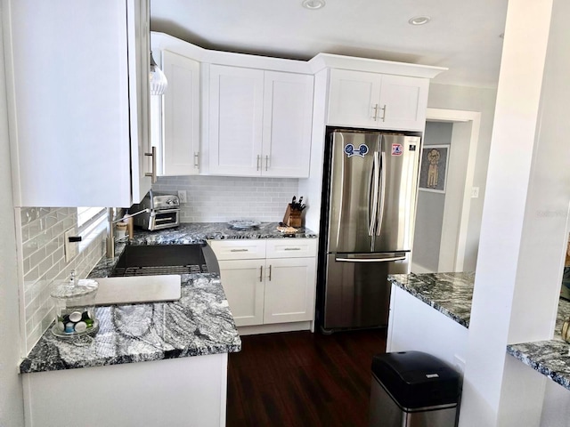 kitchen featuring stainless steel fridge, dark stone countertops, tasteful backsplash, white cabinets, and dark hardwood / wood-style flooring