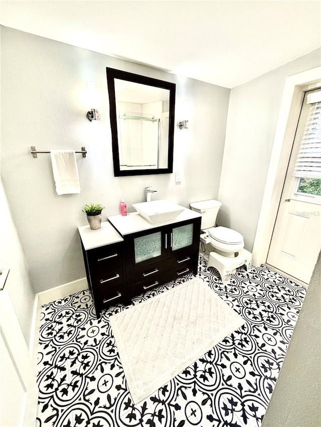 bathroom featuring vanity, a shower with shower door, and toilet