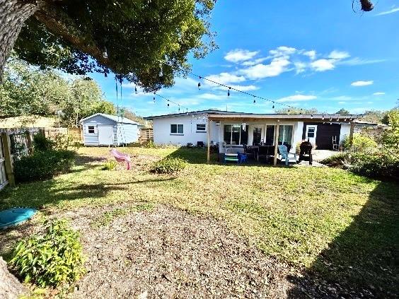 back of property featuring a storage shed and a yard