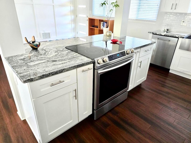 kitchen featuring dark wood-type flooring, stainless steel appliances, light stone counters, tasteful backsplash, and white cabinets