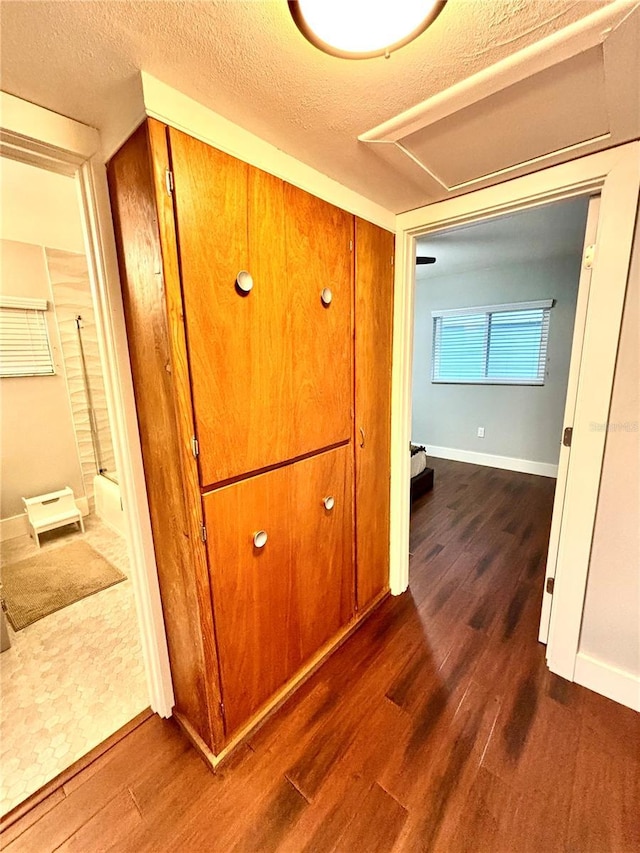 hall with a textured ceiling and dark hardwood / wood-style flooring