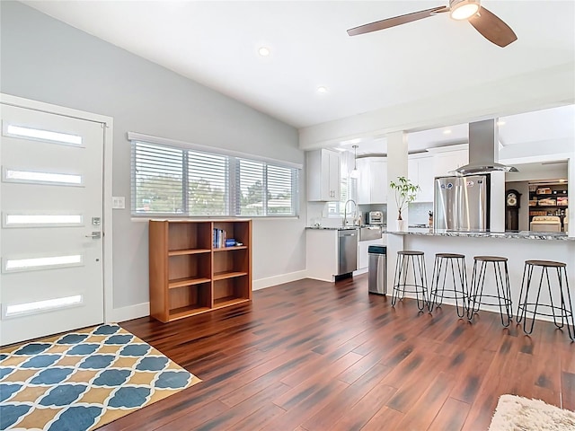 kitchen featuring a breakfast bar, lofted ceiling, dark wood finished floors, appliances with stainless steel finishes, and island range hood