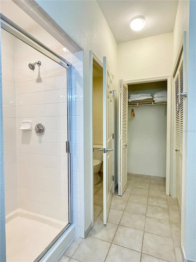 bathroom with walk in shower, toilet, tile patterned flooring, and a textured ceiling