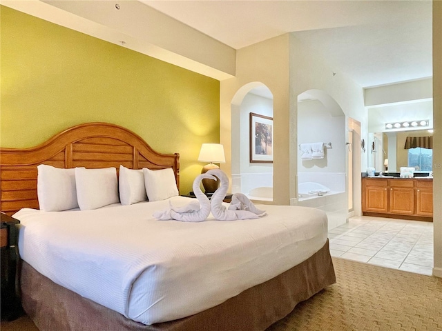 bedroom featuring ensuite bathroom and light tile patterned floors