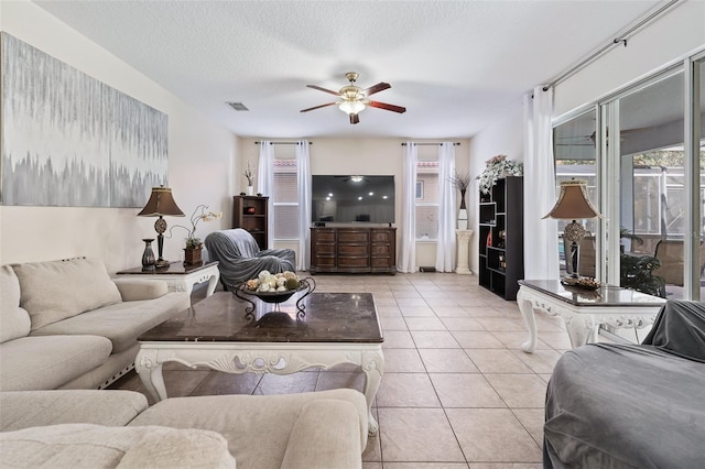 tiled living room with ceiling fan and a textured ceiling