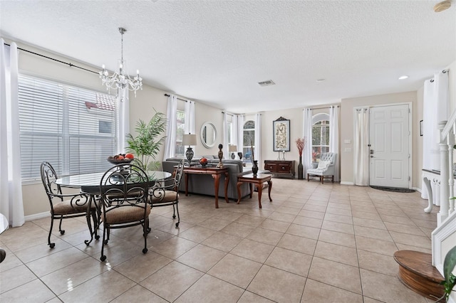 dining space with a chandelier, a textured ceiling, and light tile patterned floors