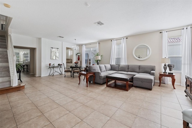 tiled living room with a notable chandelier and a textured ceiling