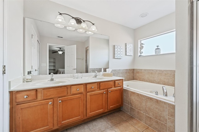 bathroom with tile patterned flooring, tiled bath, ceiling fan, and vanity