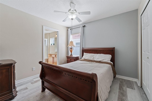 bedroom featuring ceiling fan, light wood-type flooring, a textured ceiling, ensuite bath, and a closet