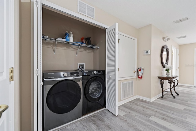 clothes washing area with separate washer and dryer and light wood-type flooring