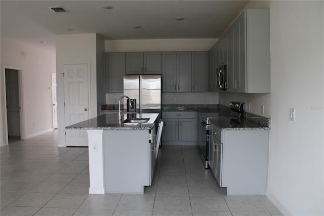1280 Tupelo Trl, Haines City, FL 33844 - kitchen with a kitchen island with sink, light tile patterned floors, gray cabinetry, and appliances with stainless steel finishes
