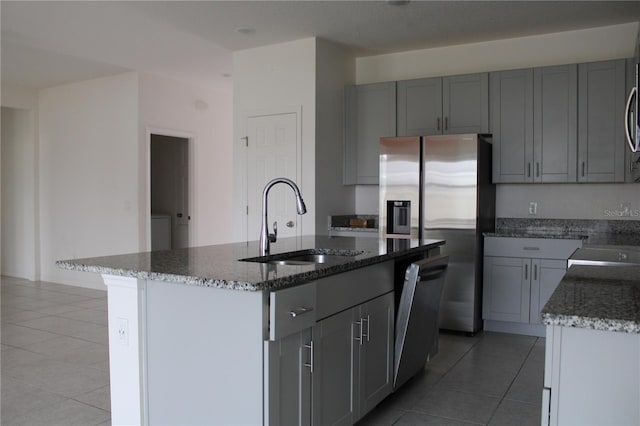 1280 Tupelo Trl, Haines City, FL 33844 - kitchen with sink, light tile patterned floors, appliances with stainless steel finishes, a kitchen island with sink, and dark stone counters