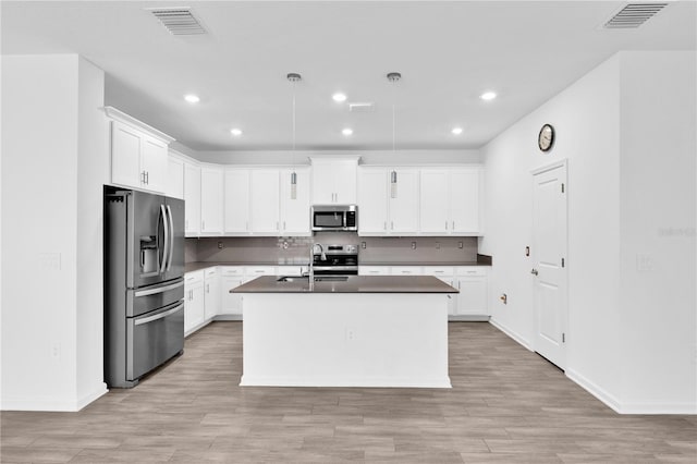 kitchen featuring stainless steel appliances, a sink, visible vents, light wood-type flooring, and dark countertops