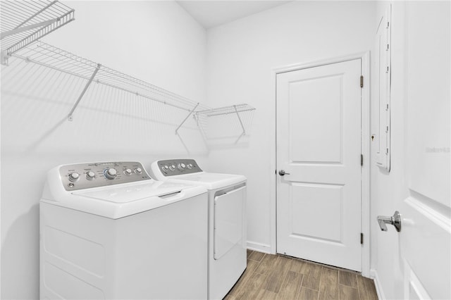 laundry area with laundry area, wood finished floors, washing machine and dryer, and baseboards