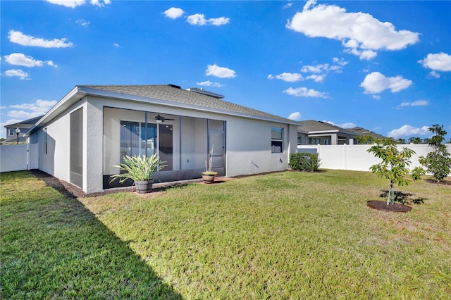 back of property featuring ceiling fan, a sunroom, and a lawn