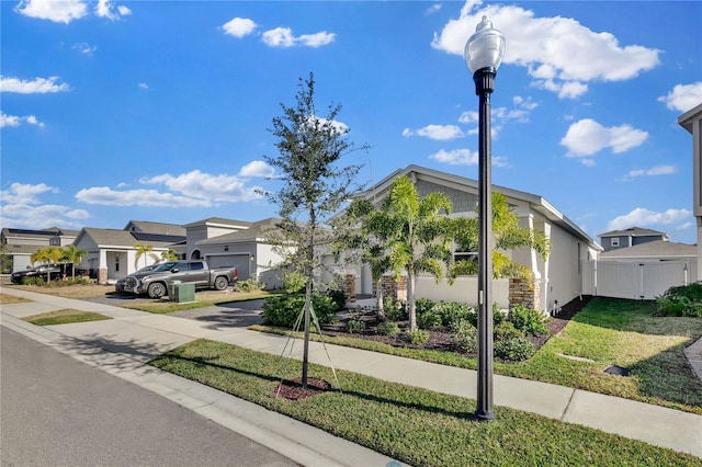 view of front facade with driveway, a residential view, fence, and stucco siding