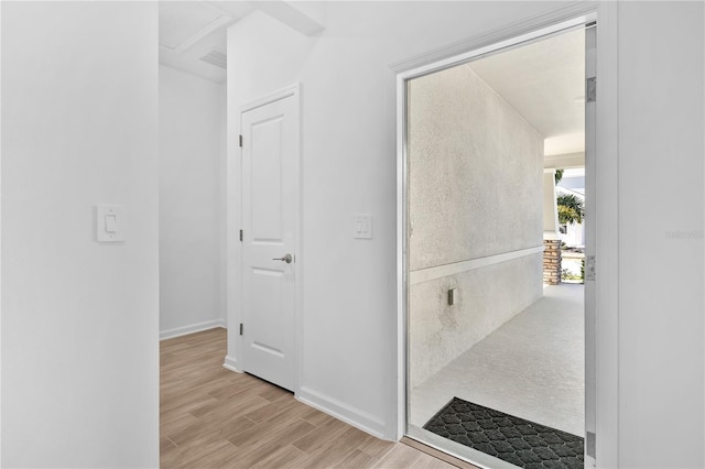 hall with visible vents, light wood-style flooring, and baseboards