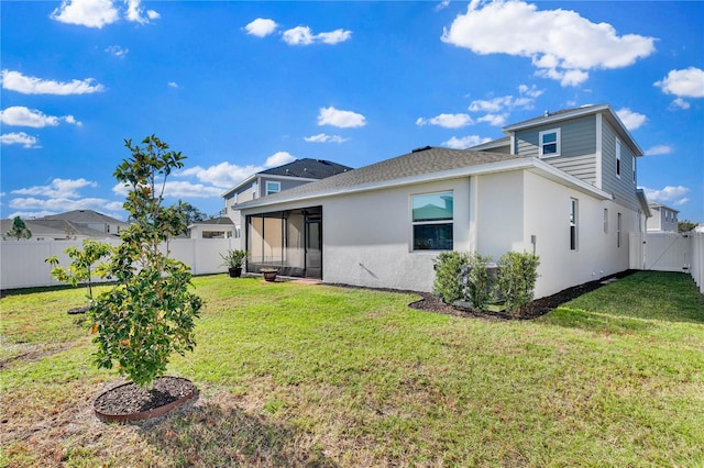 back of property featuring a lawn, a fenced backyard, a sunroom, and stucco siding