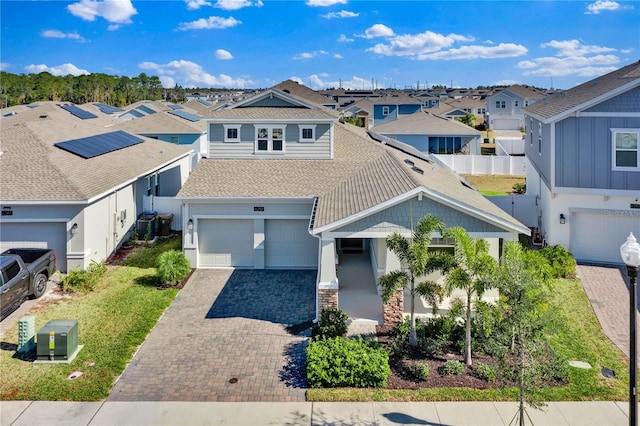 view of front of home featuring a shingled roof, a residential view, fence, and decorative driveway