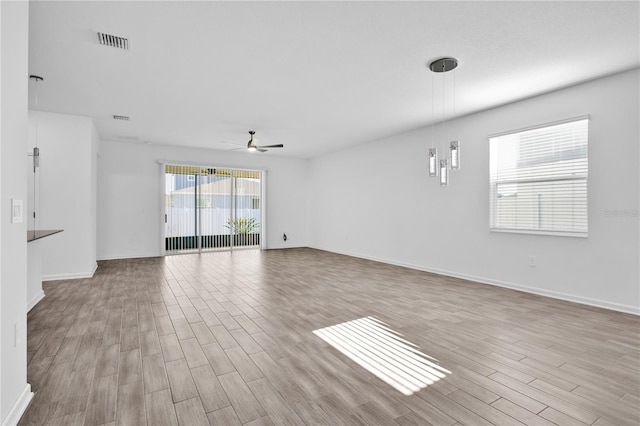 empty room featuring baseboards, wood finished floors, visible vents, and a ceiling fan