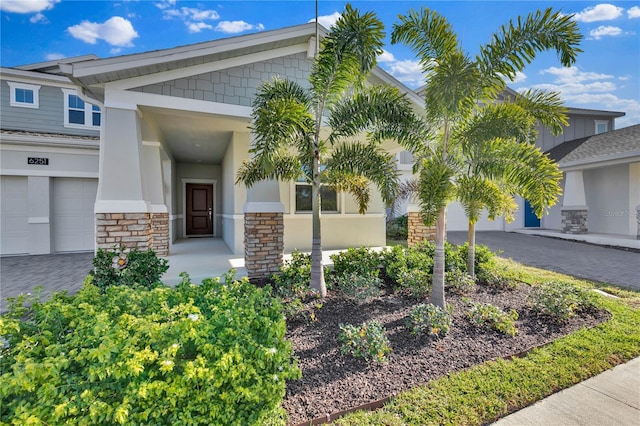 exterior space with a garage, stone siding, decorative driveway, and stucco siding