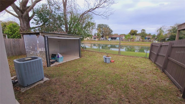 view of yard with a storage shed, central air condition unit, and a water view