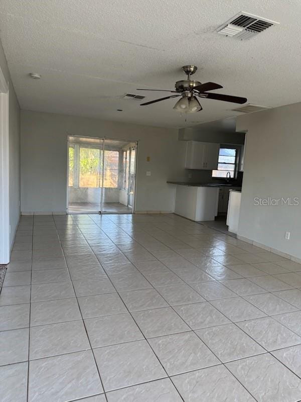 unfurnished room with ceiling fan, a textured ceiling, and light tile patterned flooring