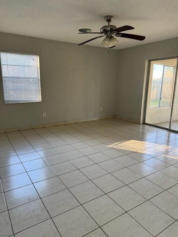 tiled spare room with ceiling fan, plenty of natural light, and a textured ceiling