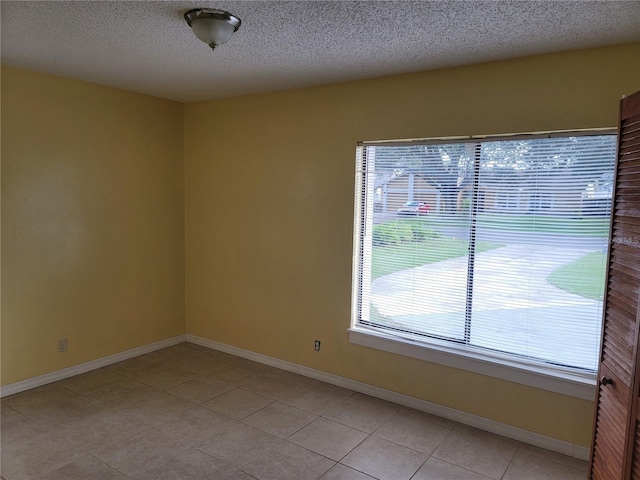 empty room with light tile patterned flooring and a textured ceiling