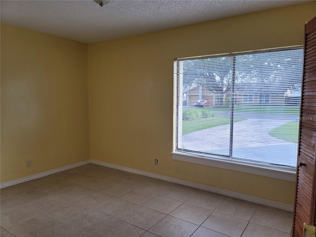 tiled spare room featuring a healthy amount of sunlight and a textured ceiling