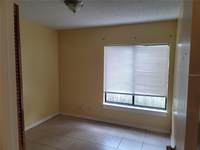 spare room with a textured ceiling and light tile patterned flooring