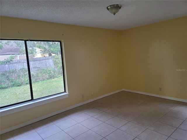 tiled spare room with a textured ceiling and a wealth of natural light