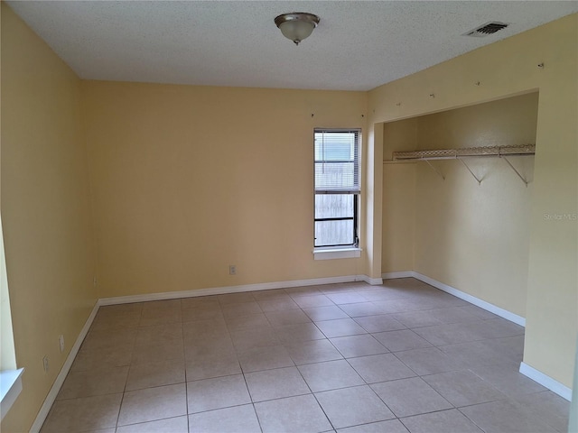 unfurnished bedroom featuring a closet, a textured ceiling, and light tile patterned flooring