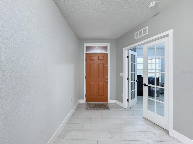 foyer entrance featuring french doors and a textured ceiling