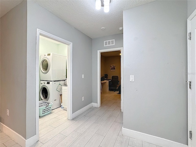 laundry room with stacked washer and dryer and a textured ceiling