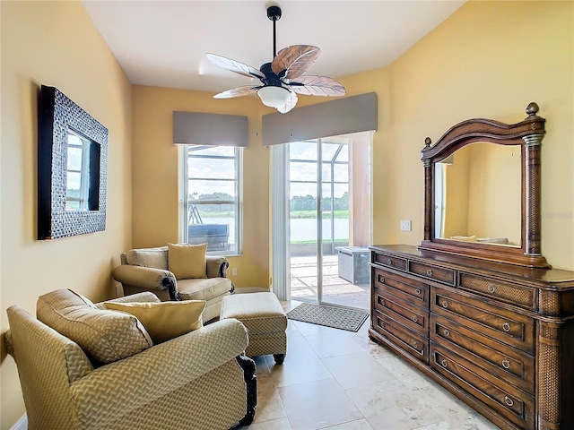 living area with light tile patterned floors and ceiling fan