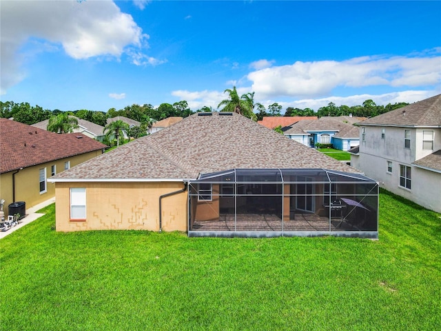 back of property with glass enclosure and a lawn