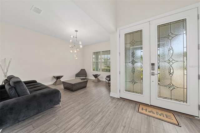 foyer entrance featuring an inviting chandelier, french doors, and light wood-type flooring